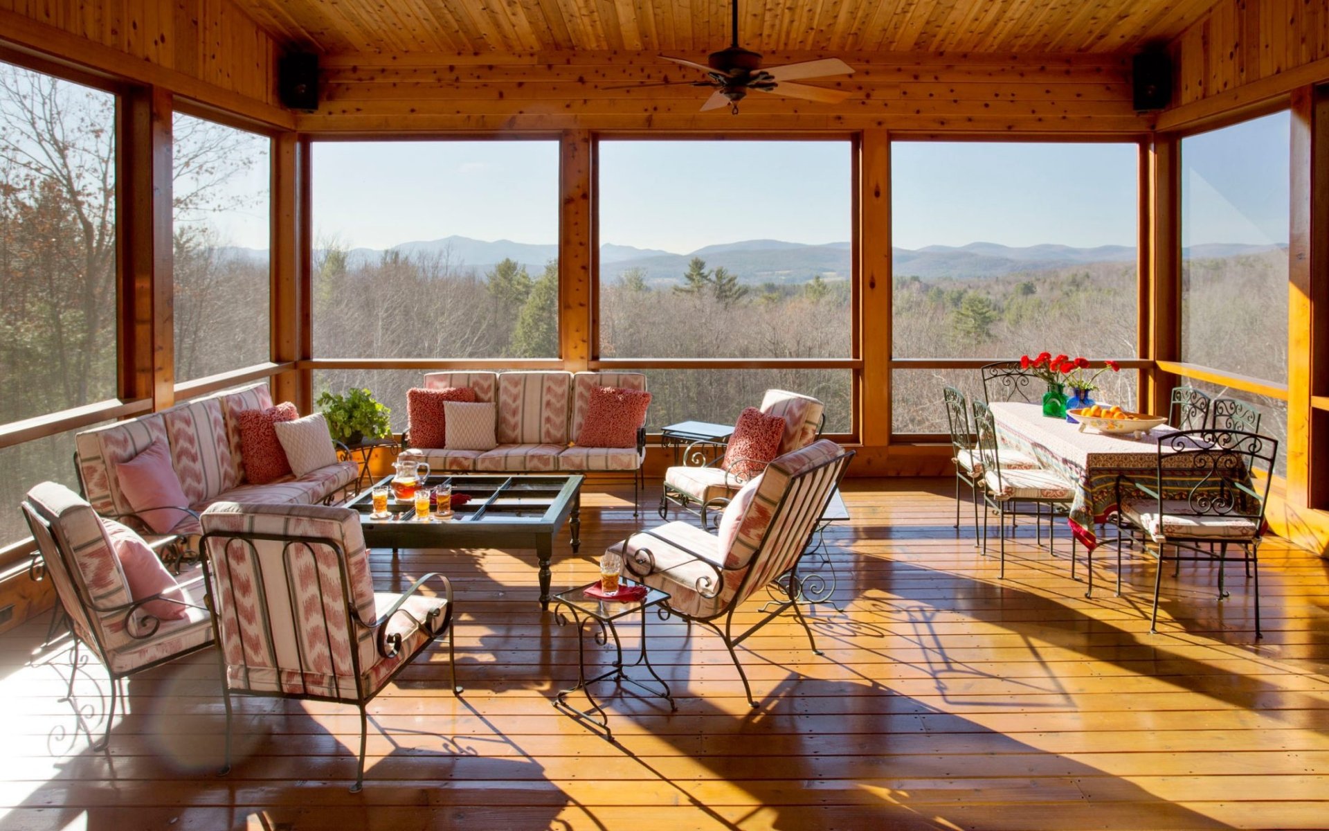 A sunlit living room with wooden furniture and large windows showcasing a mountain view, captured in an HD PC desktop wallpaper and background.