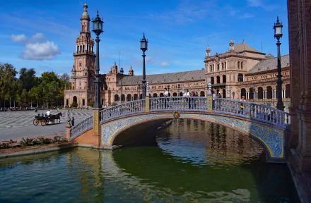 HD desktop wallpaper featuring the ornate bridge and architecture of Plaza de España in Spain under a bright blue sky.