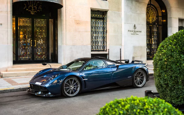 A sleek blue Pagani Huayra supercar parked outside an elegant building, captured in HD for a striking PC desktop wallpaper and background.