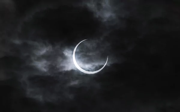 HD PC desktop wallpaper showing a dramatic eclipse with the moon partially obscuring the sun, framed by dark, swirling clouds in a natural night sky.