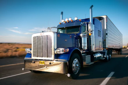 HD desktop wallpaper featuring a blue Peterbilt truck driving on a highway under a clear sky.