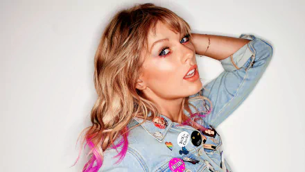 HD PC desktop wallpaper featuring singer Taylor Swift with blonde and pink hair tips, wearing a denim jacket adorned with colorful pins, against a white background.