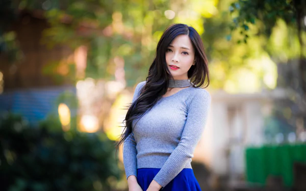 4K Ultra HD PC desktop wallpaper of a woman model with long black hair, shallow depth-of-field bokeh background, posing outdoors in soft natural light.