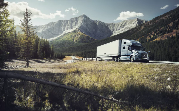 Volvo truck driving through a scenic mountain landscape, captured in stunning 8K Ultra HD for a PC desktop wallpaper background.