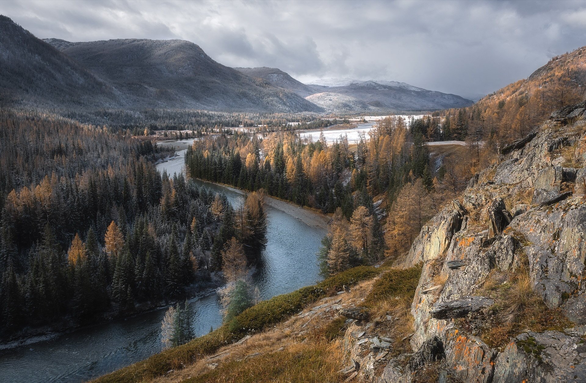 HD desktop wallpaper showcasing a serene mountain landscape with a winding river through a forested valley under a cloudy sky.