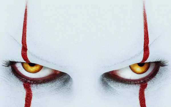 Close-up of Pennywise's menacing yellow eyes and red makeup from the movie It Chapter Two, featured in a high-definition PC desktop wallpaper.