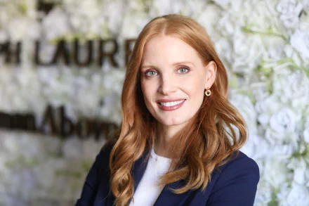 Portrait of American actress Jessica Chastain smiling, showcasing her blue eyes and red hair, featured in an HD PC desktop wallpaper background.
