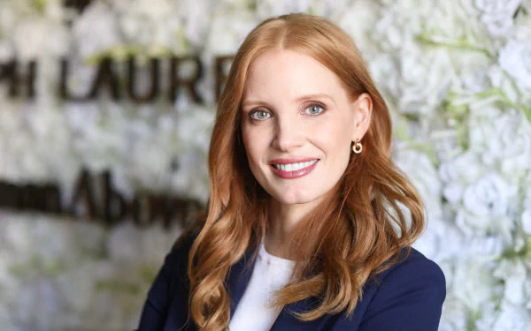 Portrait of American actress Jessica Chastain smiling, showcasing her blue eyes and red hair, featured in an HD PC desktop wallpaper background.