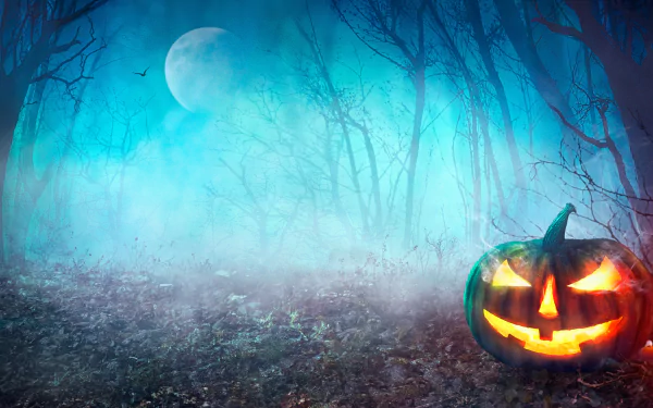 A glowing jack-o'-lantern illuminates a foggy forest under a full moon, creating a spooky Halloween scene in 4K Ultra HD for a PC desktop wallpaper.
