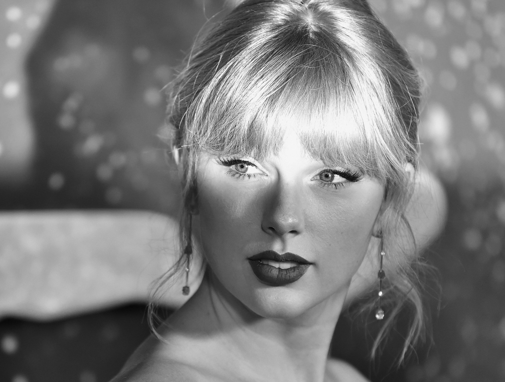 Black and white HD desktop wallpaper of American singer Taylor Swift with blonde hair, softly illuminated against a blurred background.
