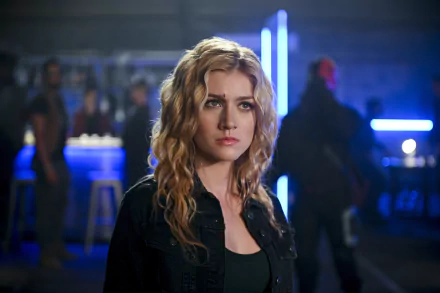HD desktop wallpaper featuring Katherine McNamara as Mia Smoak, the blonde American actress from the TV show Arrow, in a dimly lit, futuristic setting.