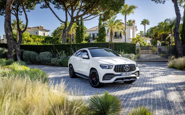 4K Ultra HD desktop wallpaper of a white Mercedes-AMG GLE 53 SUV (Mercedes-Benz) parked on a cobblestone drive before a gated villa with palm trees.