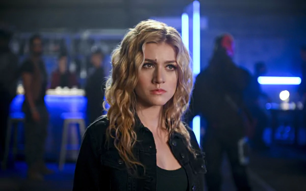 HD desktop wallpaper featuring Katherine McNamara as Mia Smoak, the blonde American actress from the TV show Arrow, in a dimly lit, futuristic setting.