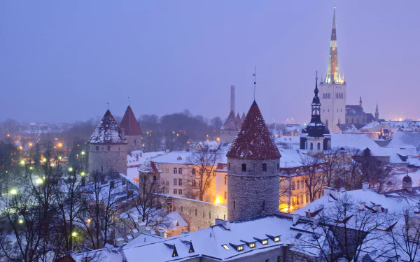 Snow-covered rooftops and historic buildings of Tallinn glow warmly under dusk light in this 4K Ultra HD winter cityscape wallpaper.