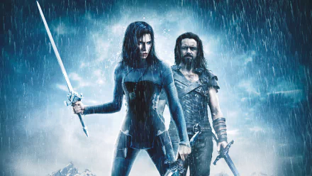 Kate Beckinsale and a male character stand in the rain wielding swords in a dramatic 4K Ultra HD wallpaper from the movie Underworld: Rise of the Lycans.