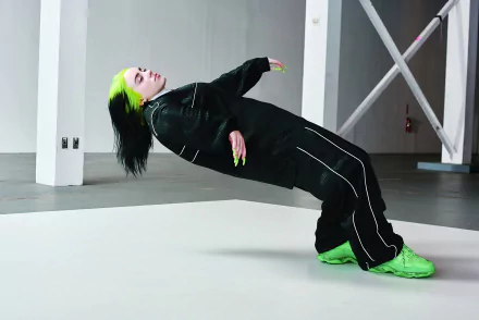 4K Ultra HD wallpaper featuring American singer Billie Eilish in a dynamic pose, showcasing her signature green and black style against a minimalist industrial backdrop.