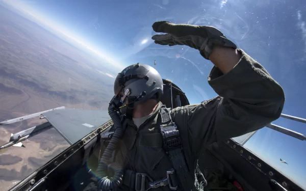 Pilot in a General Dynamics F-16 Fighting Falcon cockpit salutes above a desert; dynamic 5K Ultra HD desktop wallpaper of a military jet and pilot in flight.