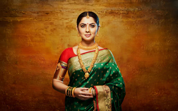HD PC desktop wallpaper: portrait of a model with black hair in a green-and-red saree, wearing ornate earrings, a necklace and bangles against a textured golden-brown backdrop.