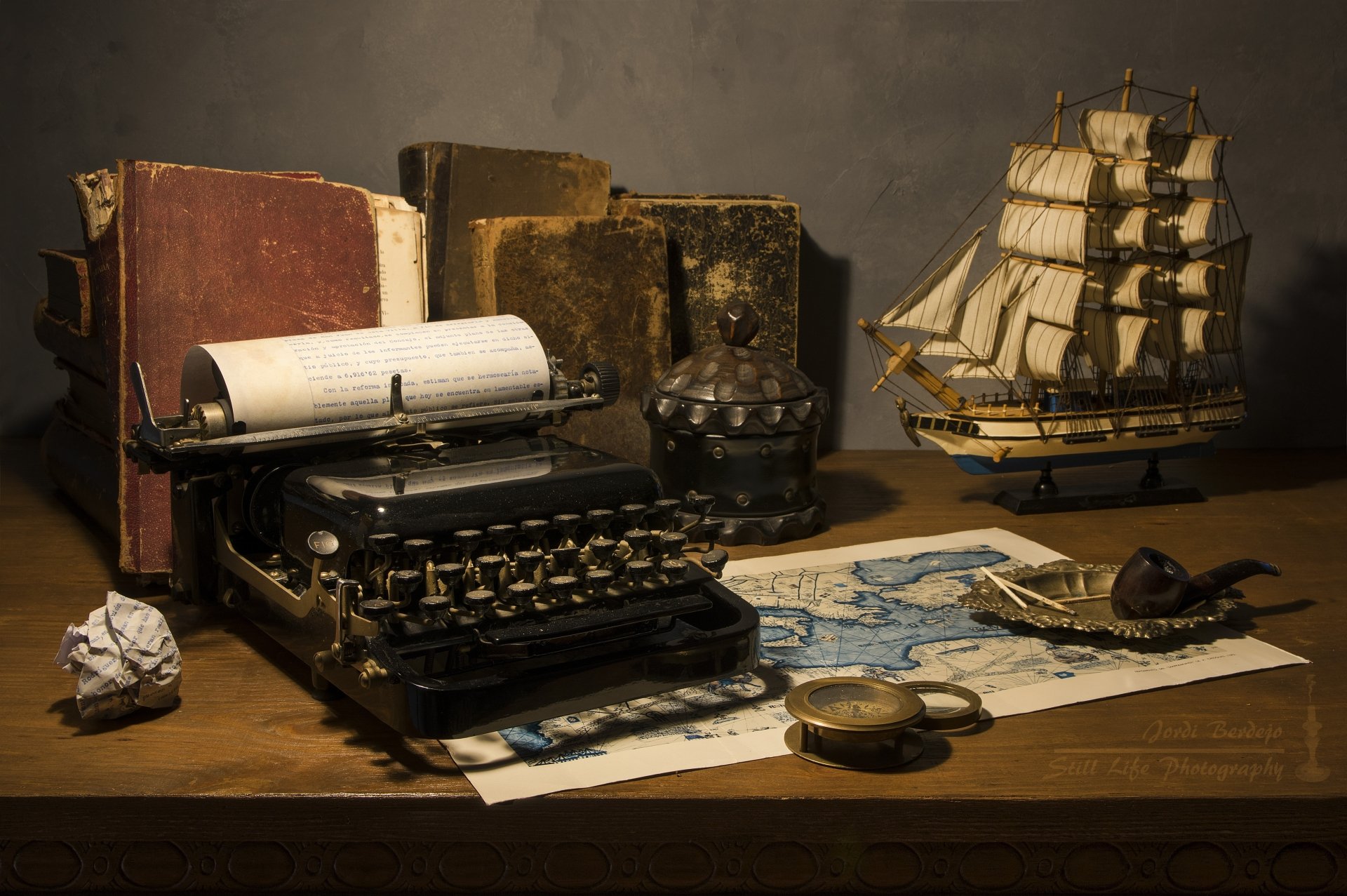 5K Ultra HD PC desktop wallpaper still-life photography: vintage typewriter, old books, nautical map, compass, smoking pipe and model ship arranged on a wooden desk.