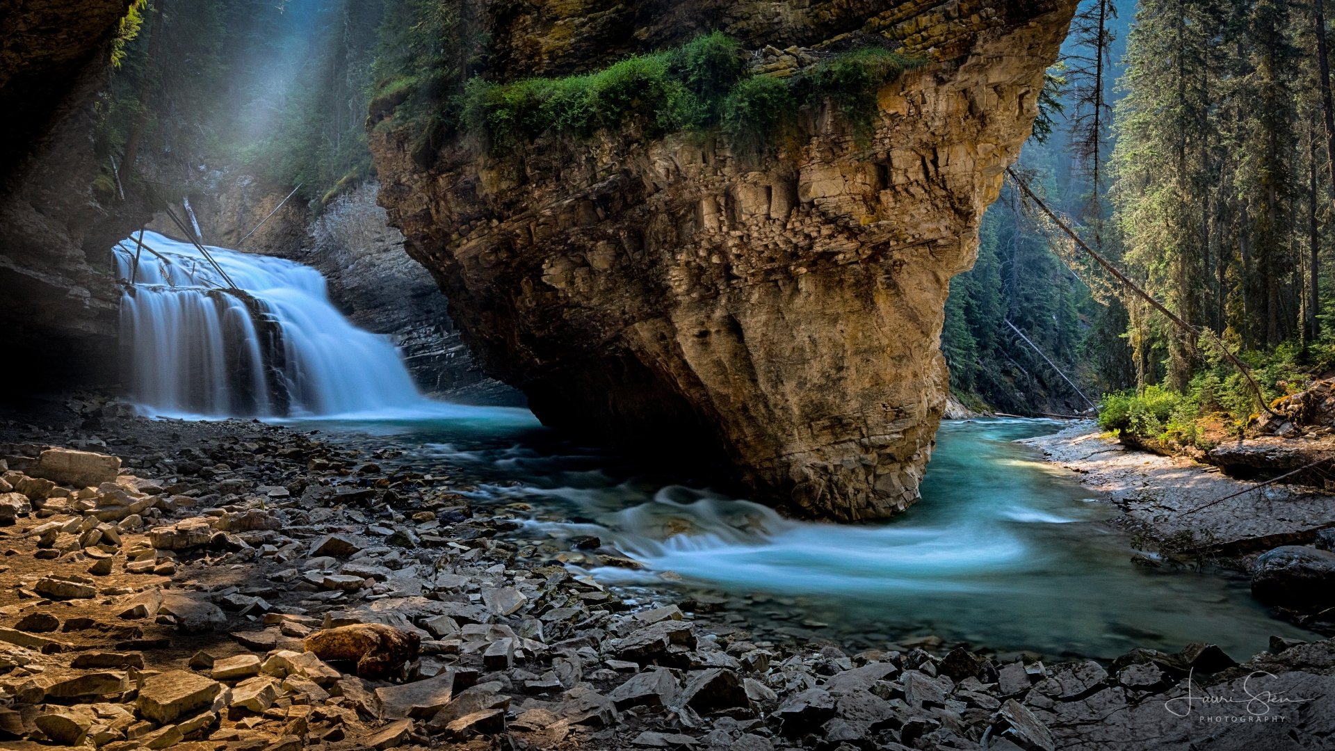 Scenic 4K Ultra HD view of Johnston Canyon waterfall and river in Banff National Park, Canada, surrounded by rugged rocks and lush forest.