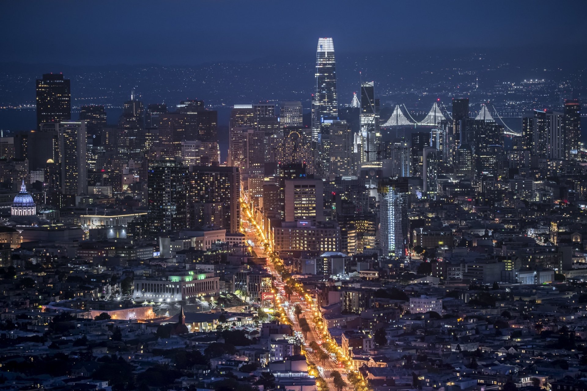 Nighttime aerial view of San Francisco cityscape with illuminated streets and skyscrapers, captured in a high-definition man-made urban setting.