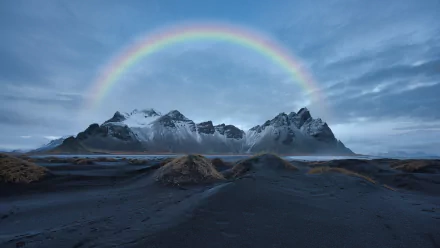 Vestrahorn Mountain in Iceland rises behind a black sand beach under a vibrant rainbow, captured in stunning 8K Ultra HD detail.