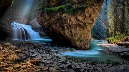 Scenic 4K Ultra HD view of Johnston Canyon waterfall and river in Banff National Park, Canada, surrounded by rugged rocks and lush forest.