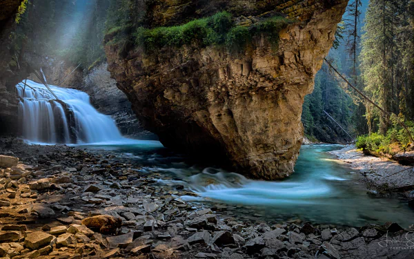 Scenic 4K Ultra HD view of Johnston Canyon waterfall and river in Banff National Park, Canada, surrounded by rugged rocks and lush forest.