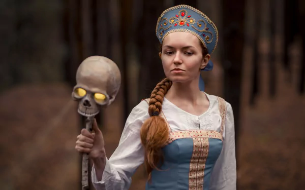 A woman in detailed witch cosplay holds a skull staff, set against a blurred forest background, captured in 4K Ultra HD as a PC desktop wallpaper.