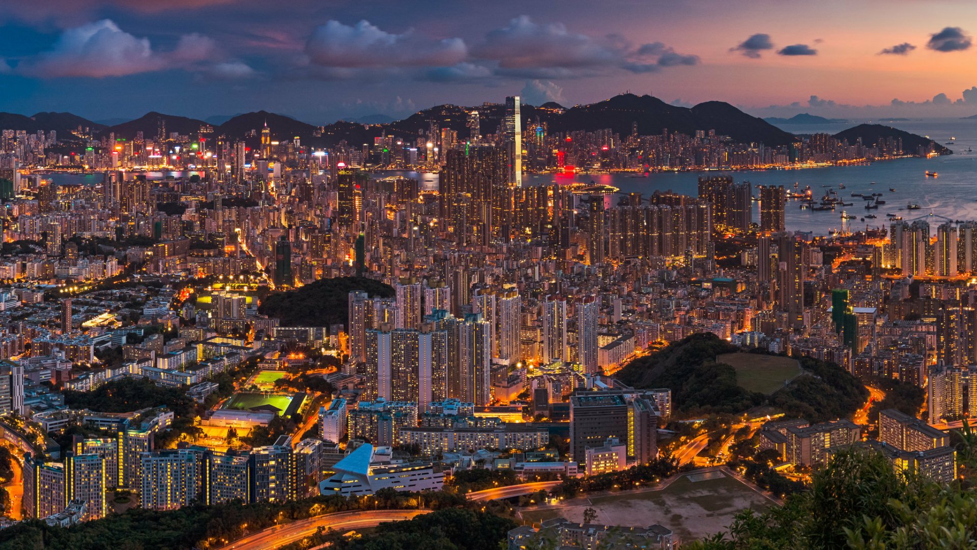 Panoramic night view of Hong Kong, China: illuminated man-made skyline and harbor with dense high-rises — HD PC desktop wallpaper background.
