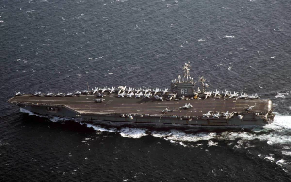 A high-definition aerial view of the USS Dwight D. Eisenhower (CVN-69) aircraft carrier underway, showcasing its military navy warship and deck full of aircraft.
