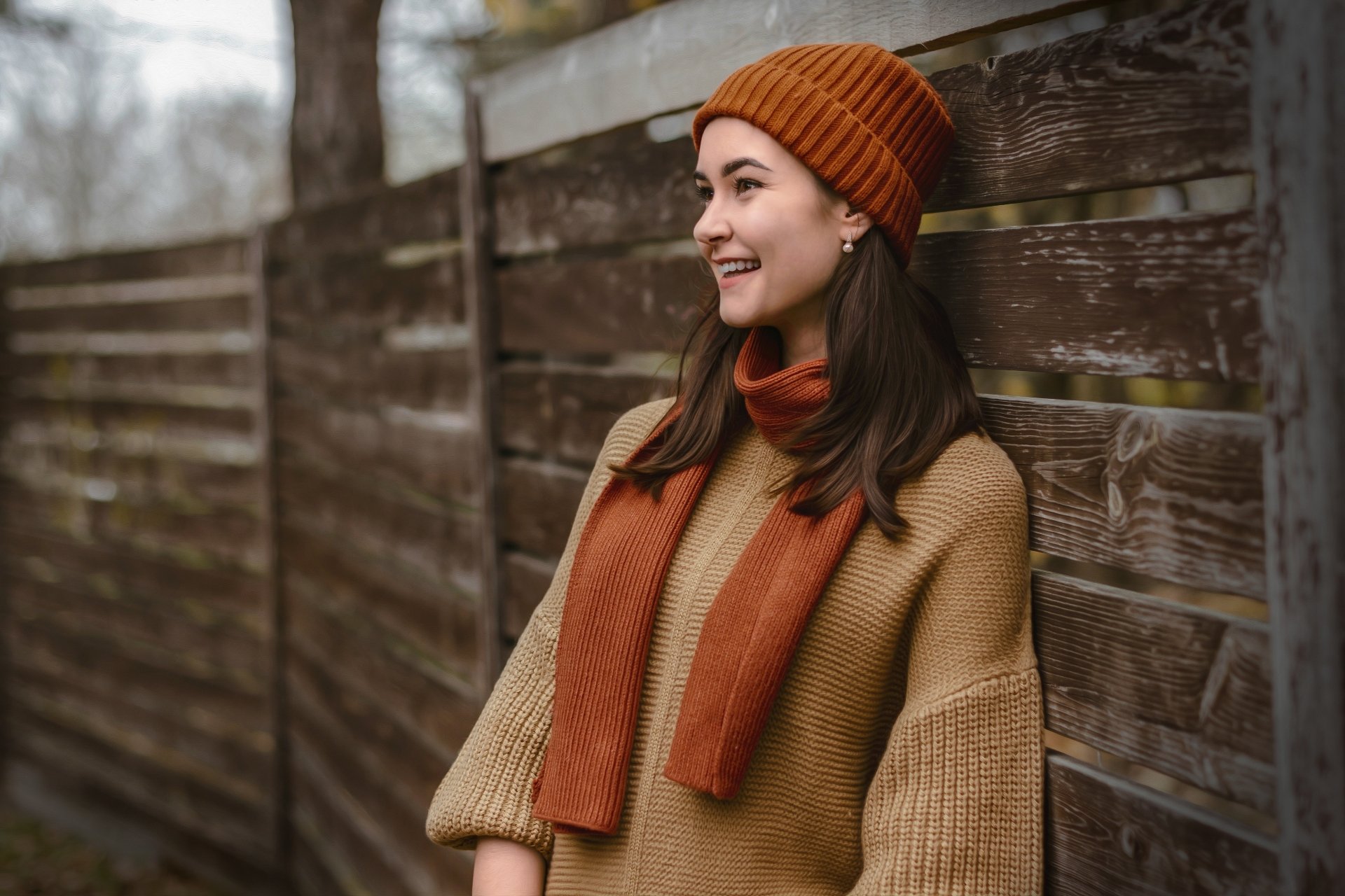 Profile of a smiling woman in a knit hat and scarf against a wooden fence — warm, relaxed mood; 4K Ultra HD PC desktop wallpaper/background.
