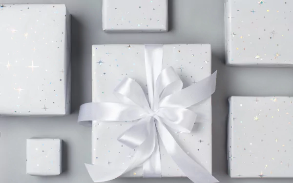 HD PC desktop wallpaper of white Christmas gift boxes with subtle star speckles and a central box tied with a glossy white ribbon — minimalist holiday gift background