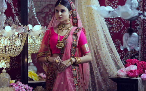 An Indian woman in traditional sari and jewelry poses gracefully with elegant makeup against an ornate, floral-decorated backdrop in this HD desktop wallpaper.