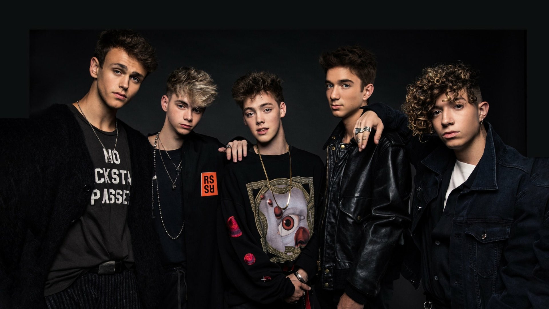 HD desktop wallpaper of the band Why Don't We, featuring five members posing against a dark background.