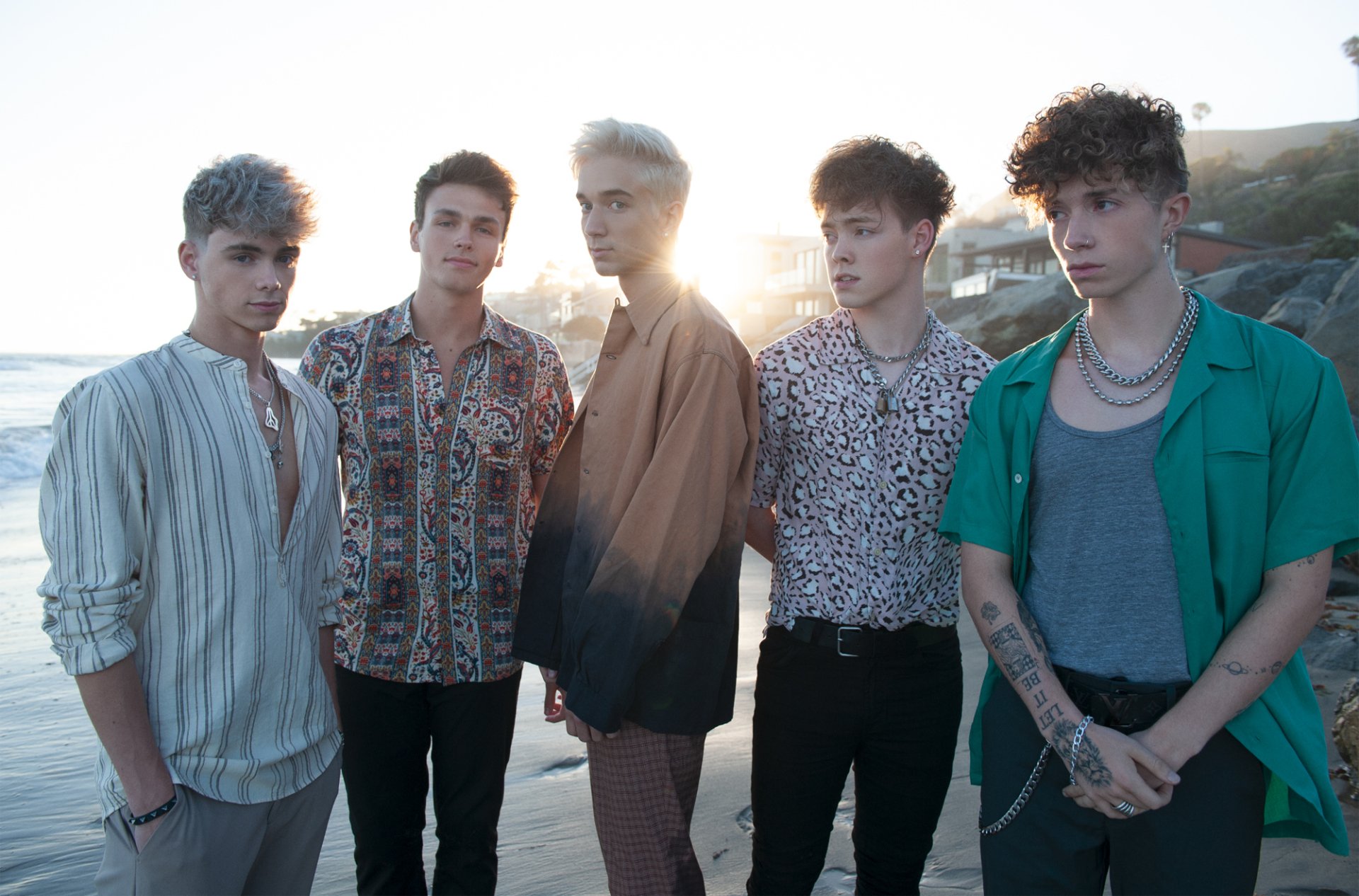 HD desktop wallpaper featuring the group Why Don't We posing together on a beach at sunset.