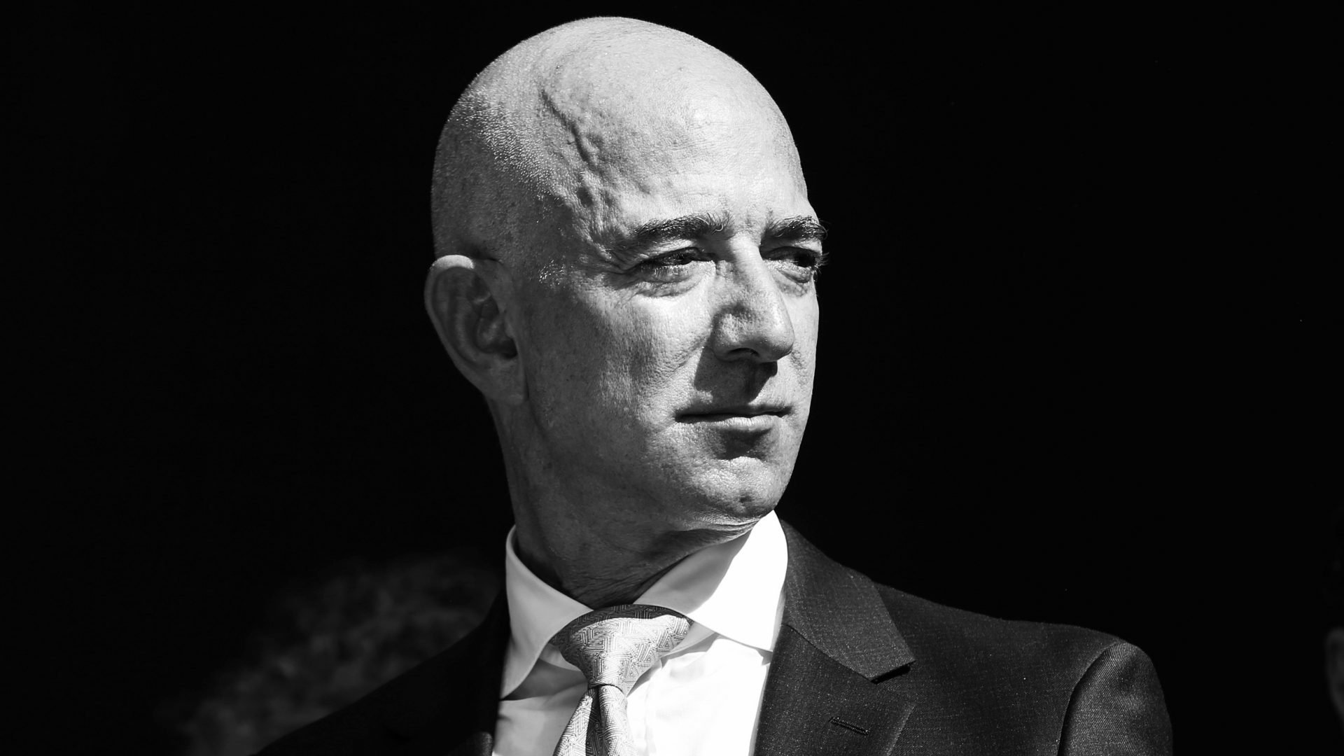 HD desktop wallpaper featuring a black and white portrait of a bald man in a suit, tagged with Jeff Bezos.