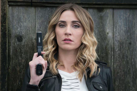 HD wallpaper featuring Jessica Harmon holding a radio, with a serious expression in front of a wooden background.