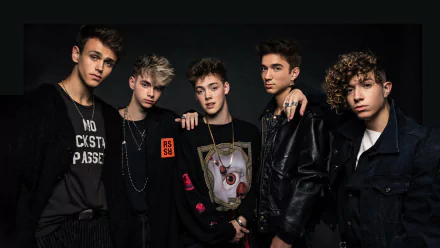 HD desktop wallpaper of the band Why Don't We, featuring five members posing against a dark background.