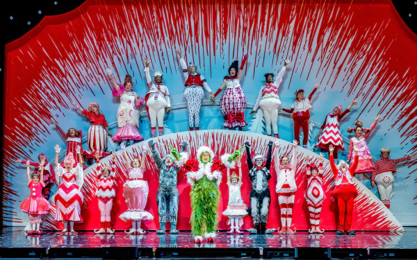 HD wallpaper of 'Dr. Seuss' The Grinch Musical' with performers on stage in colorful costumes and a festive set design.