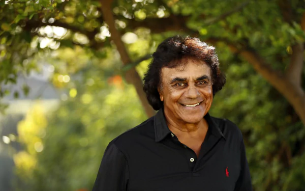 HD desktop wallpaper of a smiling man in a black shirt with a leafy green background.