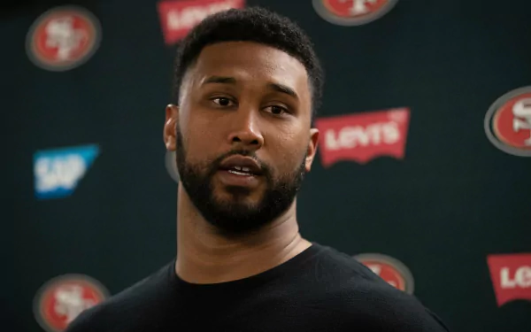 High-definition desktop wallpaper featuring DeForest Buckner, showcasing the athlete during a press conference in front of a San Francisco 49ers backdrop.