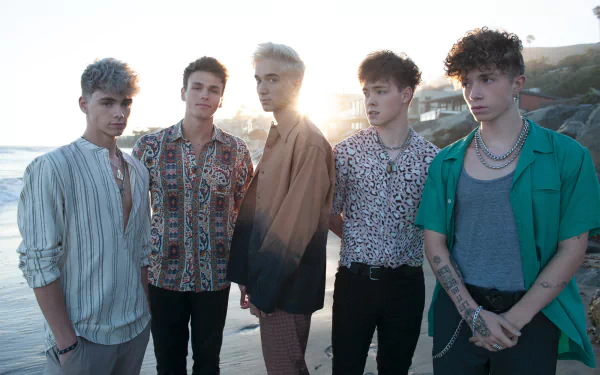 HD desktop wallpaper featuring the group Why Don't We posing together on a beach at sunset.