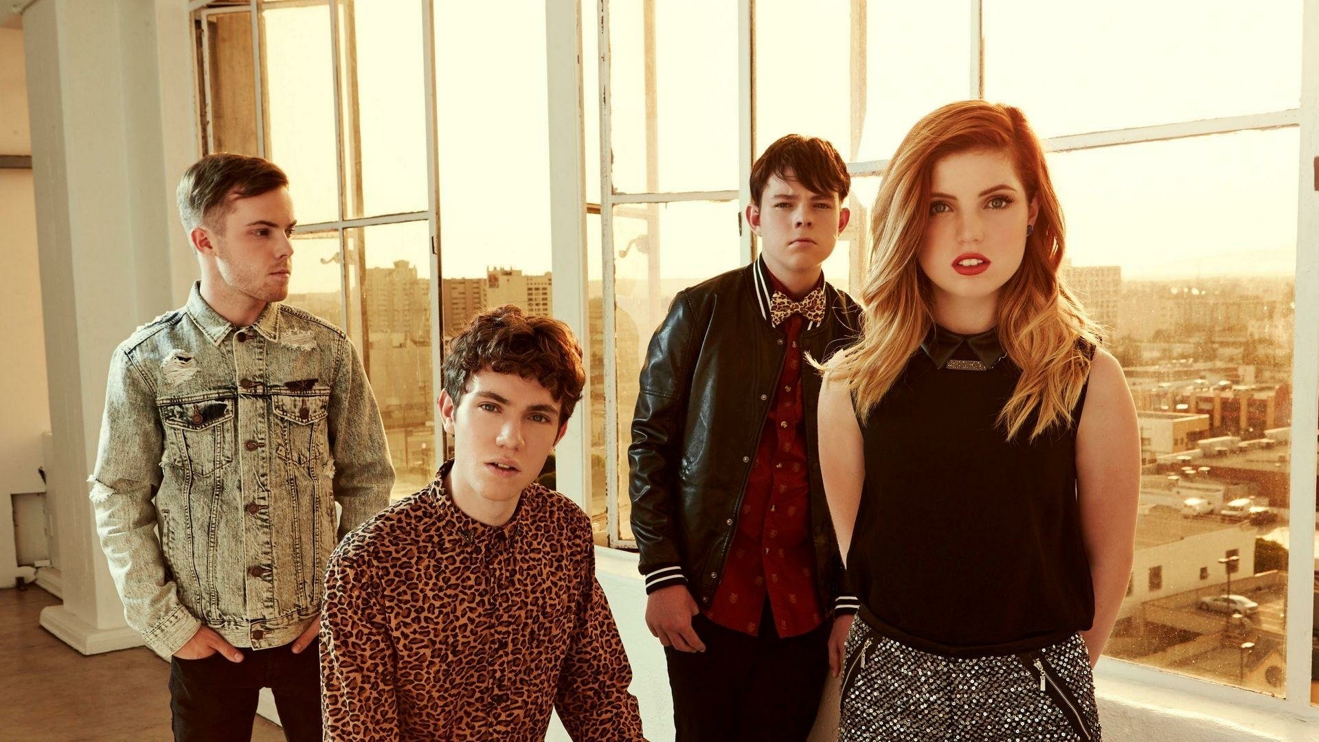 Echosmith band members, including Sydney Sierota, posing in a room with a city view, in an HD desktop wallpaper format.