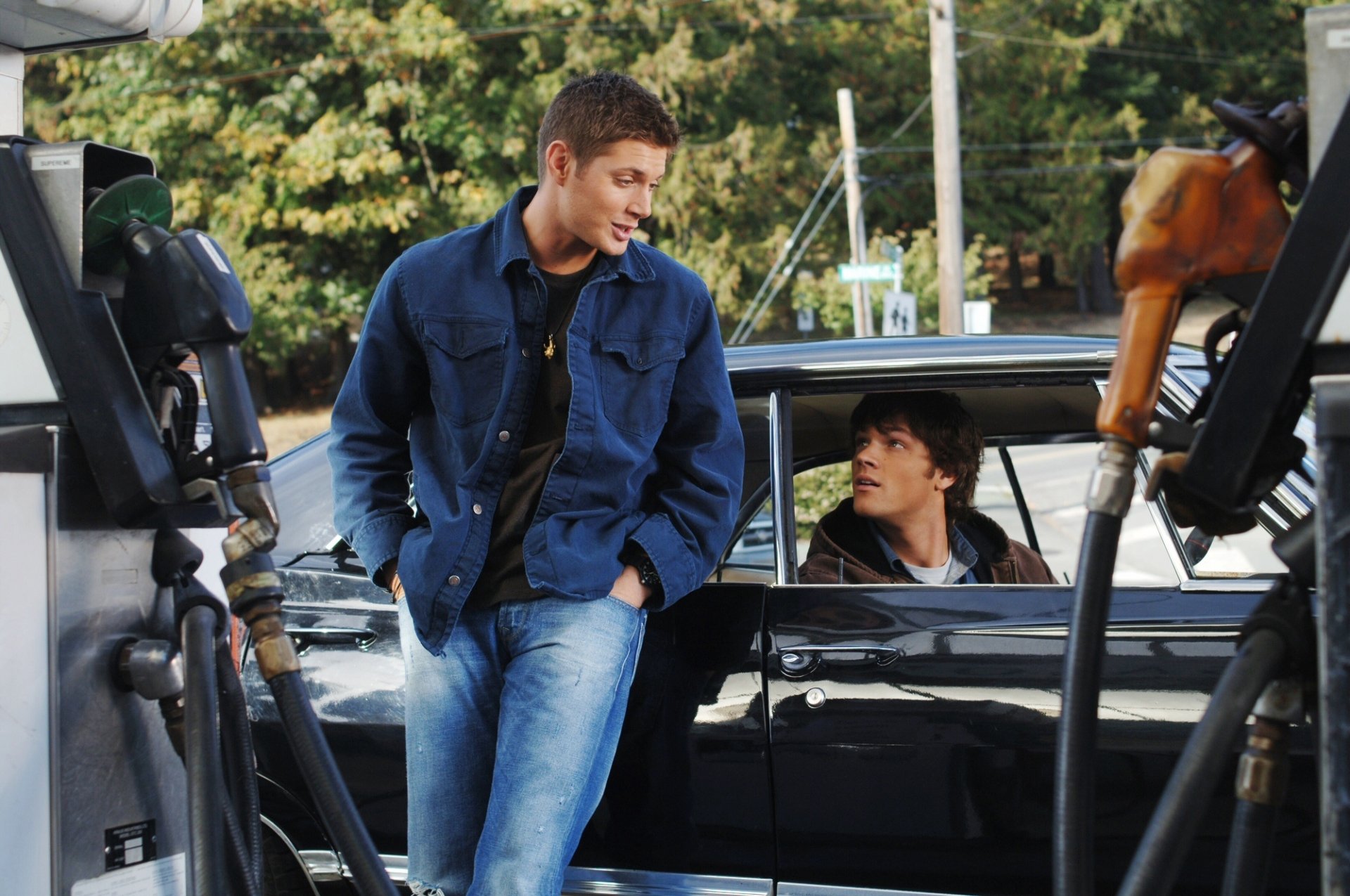 HD PC wallpaper featuring Jared Padalecki as Sam Winchester and Jensen Ackles as Dean Winchester from the TV show Supernatural at a gas station.
