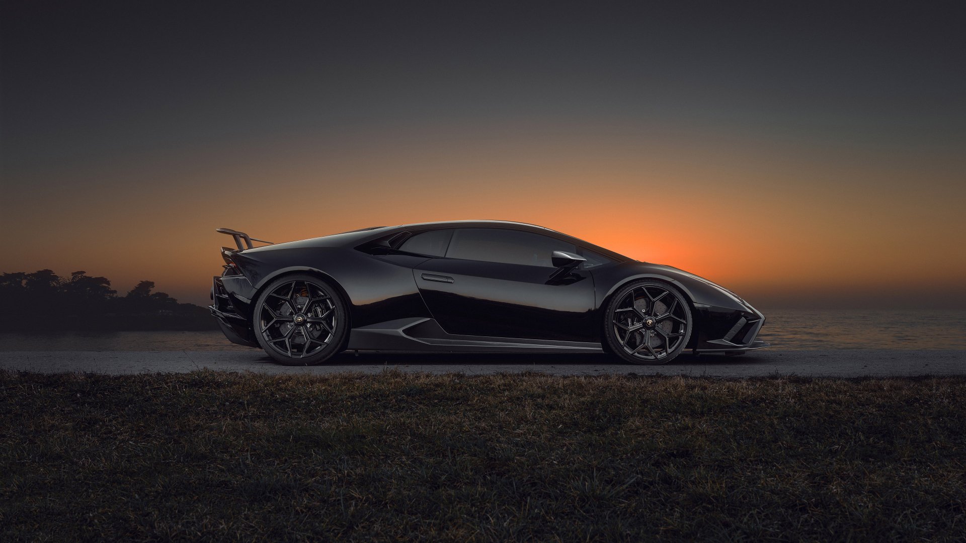 Side profile of a sleek black Lamborghini Huracan Evo supercar at sunset, 4K Ultra HD PC desktop wallpaper background.