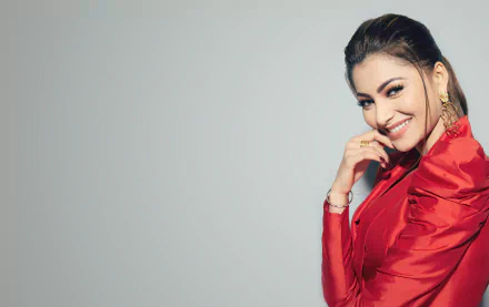 Smiling brunette woman in a red satin jacket with gold earrings, studio portrait on a pale background — 8K Ultra HD desktop wallpaper.