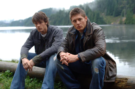 Sam Winchester and Dean Winchester from the TV show Supernatural, portrayed by Jared Padalecki and Jensen Ackles, sit by a lakeside in this 4K Ultra HD desktop wallpaper.