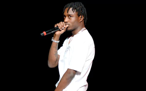 HD desktop wallpaper featuring a person with a microphone against a black background, tagged with Lil Tjay.