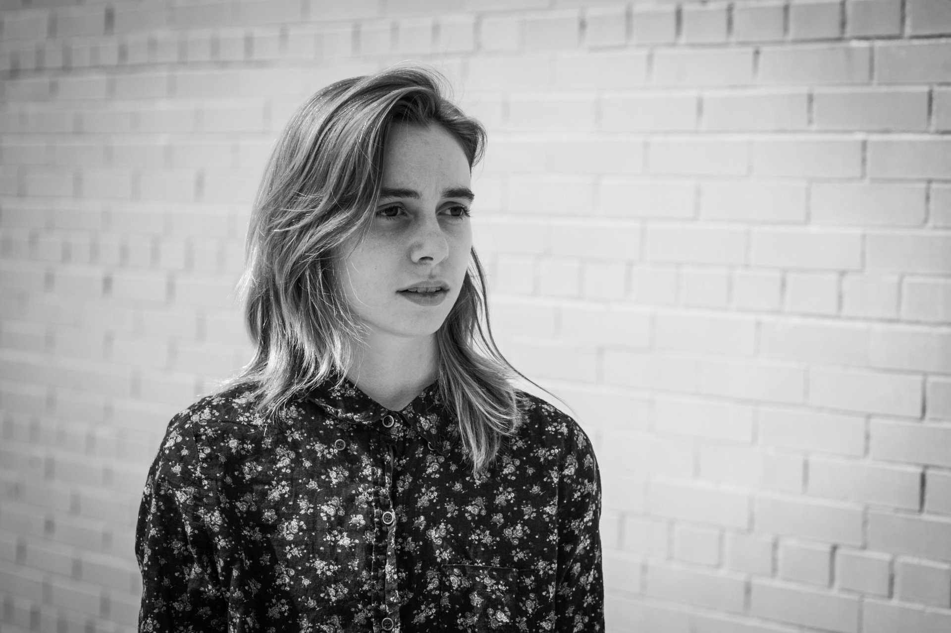 HD desktop wallpaper featuring a black and white photo of a person standing against a brick wall, evoking a contemplative mood.